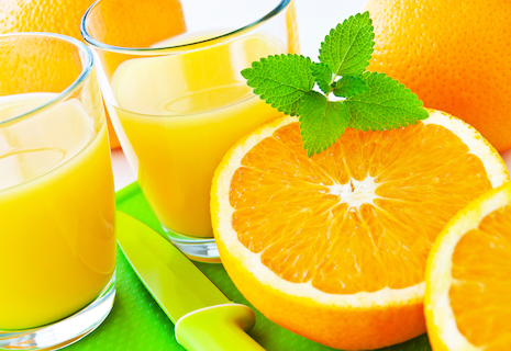 sliced oranges and glasses of orange juice on bright green placemat