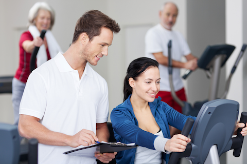pregnant woman on exercise bike with male personal trainer