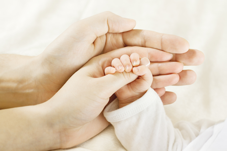 closeup of man and woman and baby's hands together