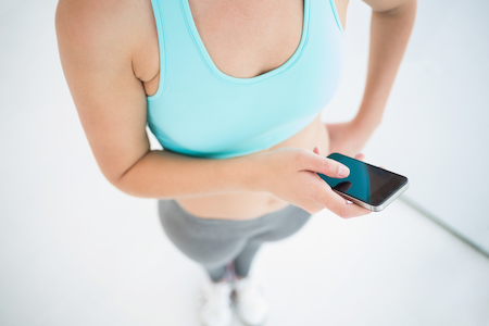 pregnant woman in a sports bra holding a mobile phone