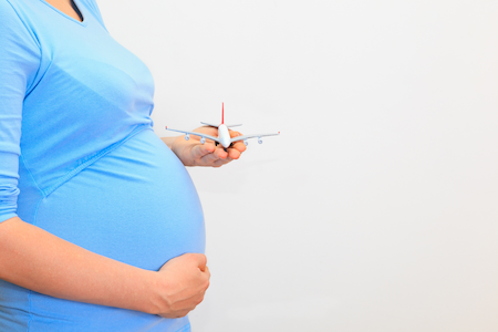 pregnant woman holding miniature airplane