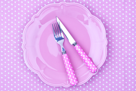 pink silverwear and plate on polka-dotted pink setting 