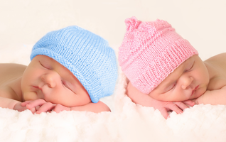 two babies in hats sleeping next to each other