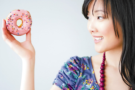 woman holding a donut with strawberry frosting
