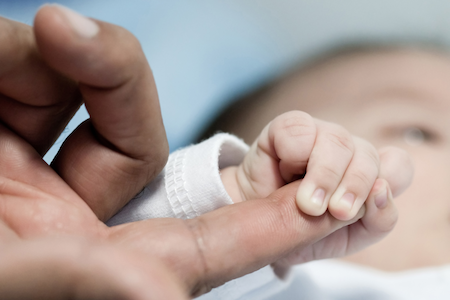 newborn baby holding father's finger