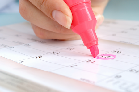 Woman circling a day on the calendar with a pink marker